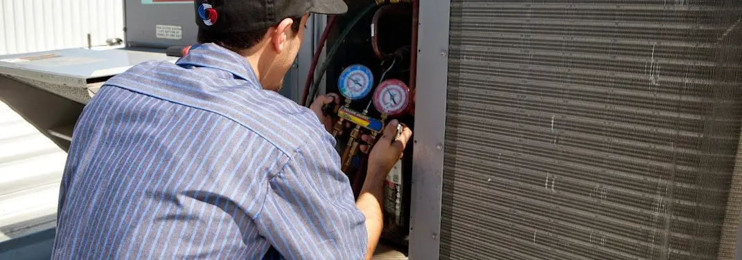 HVAC technician servicing a condenser unit in Sedalia